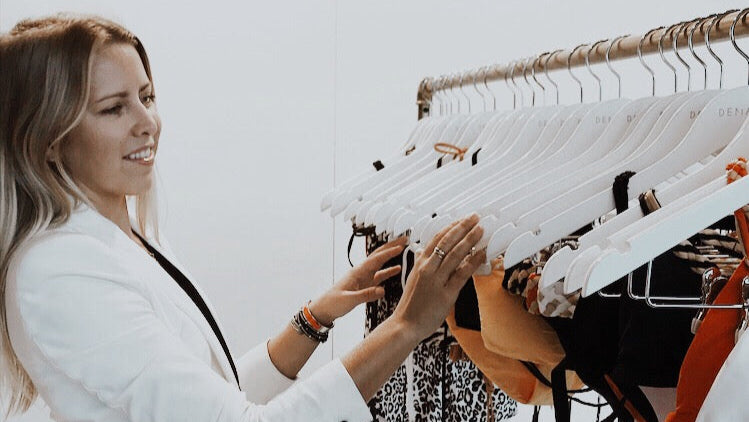 Founder of DEMADLY in a white jacket interacting with a rack of swimwear
